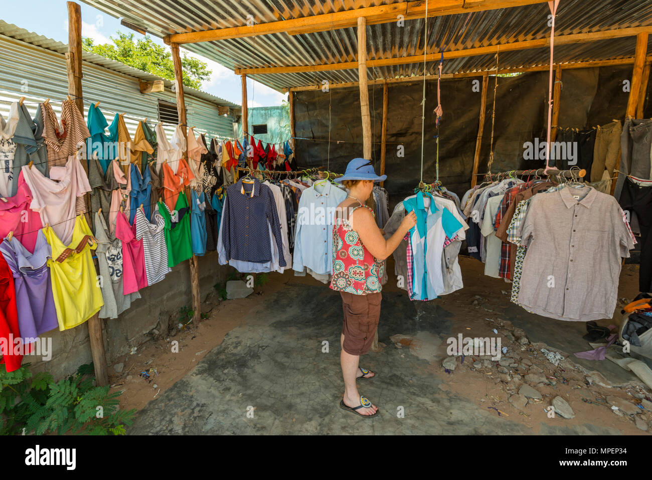 Ein Tourist durchstöbert Kleidung in einem informellen Geschäft in Inhassoro Mosambik. Stockfoto