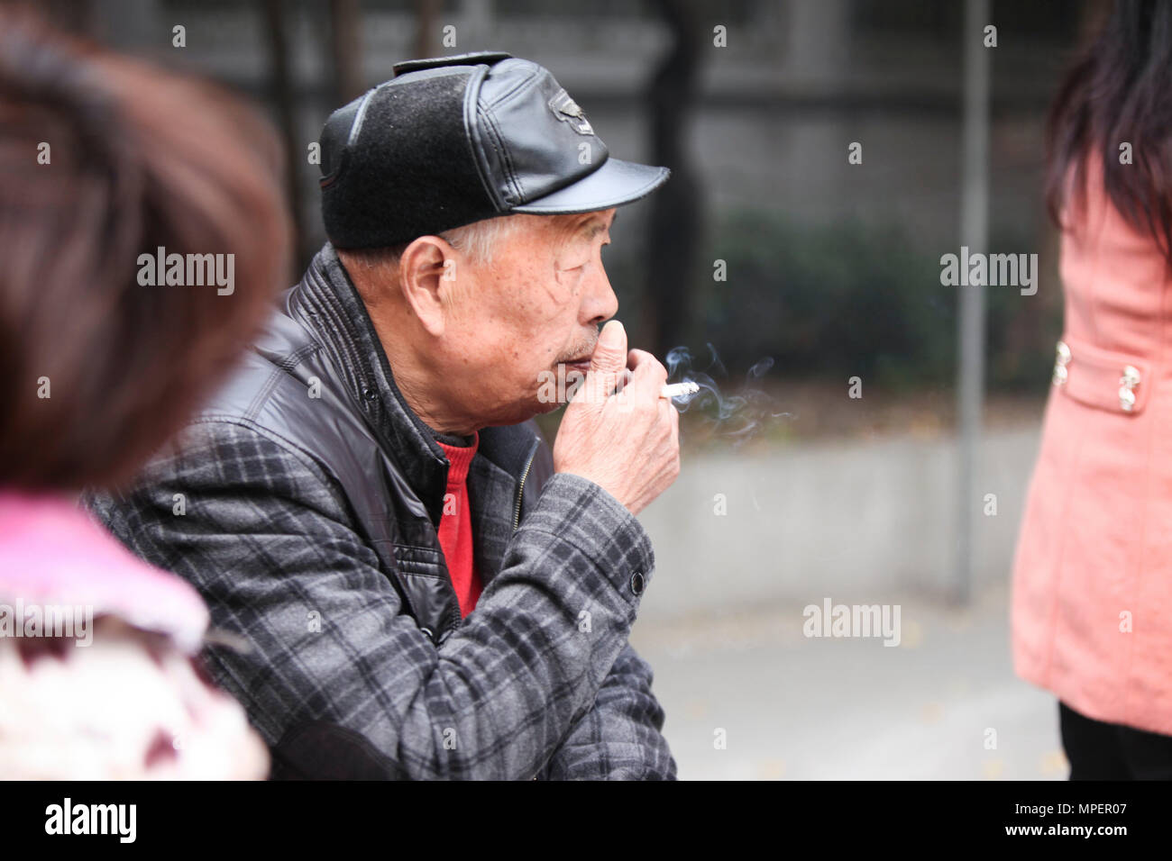Chinesische alte Mann rauchen und Glücksspiel mit einem Karten Spiel in Hangzhou, China Stockfoto