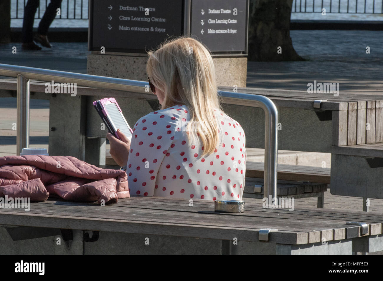 Eine junge Frau, die außerhalb der Royal Festival Hall und National Theatre in London entspannen und mit einem iPad in der warmen Sonne zu sitzen. Stockfoto