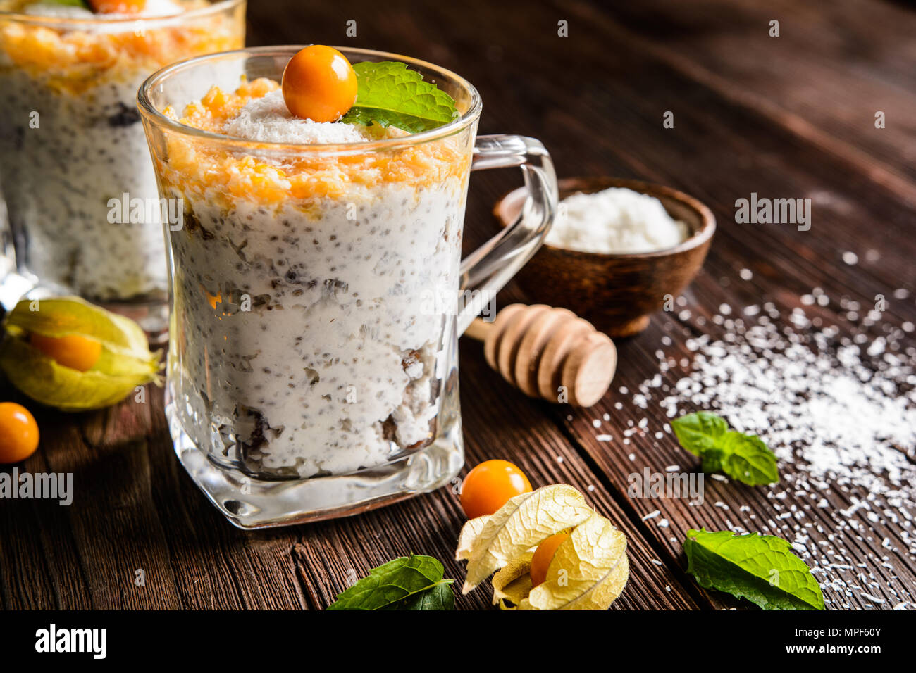 Probiotischer Joghurt mit Chia Samen, Kokos, Honig und Physalis in einem Glas Püree Stockfoto