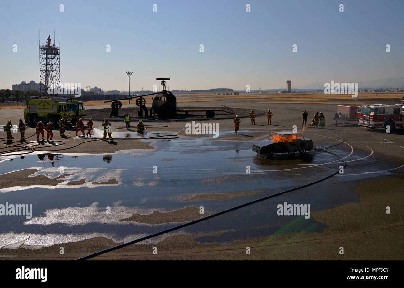 Feuerwehrleute der Japan Self-Defense Force und der 374th Civil Engineer Squadron bereiten sich auf ein Fahrzeugfeuerschulungsszenario auf der Yokota Air Base in Japan vor. Teams sind organisiert, um Brände zu löschen und Sicherheitsleitungen zu warten. Die Übung verbessert die Teamarbeit, die behördenübergreifende Koordination, die Einsatzbereitschaft, die Kenntnisse in der Brandbekämpfungsstrategie, die Notfallbereitschaft und die praktische Szenarienvorbereitung für Fahrzeugbrände, wobei die Sicherheit und Effektivität der Verfahren betont wird. Stockfoto