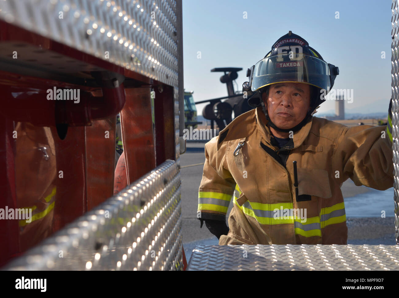 Ein Feuerwehrmann der 374th Civil Engineer Squadron klettert auf einen Feuerwehrwagen, um Schläuche für ein Feuerwehrübungsszenario auf der Yokota Air Base in Japan zu positionieren. Die Übung, die mit den japanischen Selbstverteidigungskräften und den Feuerwehren der Fussa durchgeführt wird, entwickelt Feuerwehrtechniken, Teamarbeit, Koordination, Einsatzbereitschaft, und Kompetenz zwischen den Behörden. Das Personal sammelt praktische Erfahrungen mit Brandunterdrückungs- und Notfallmaßnahmen und sorgt so für die Vorsorge bei realen Vorfällen. Stockfoto