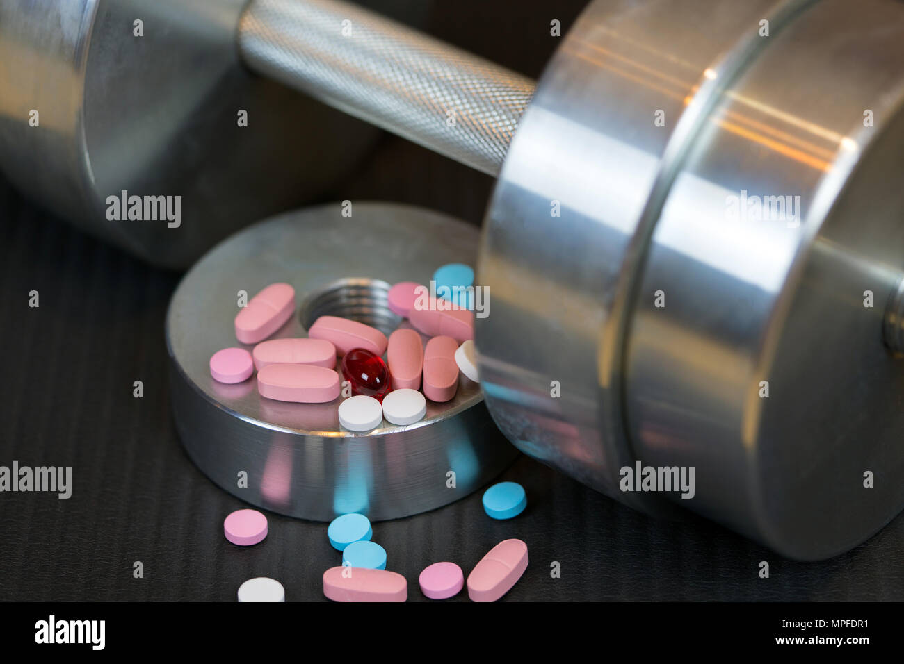 Stahl Kurzhantel und bunte Vitamine Pillen auf der Gymnastikmatte Stockfoto