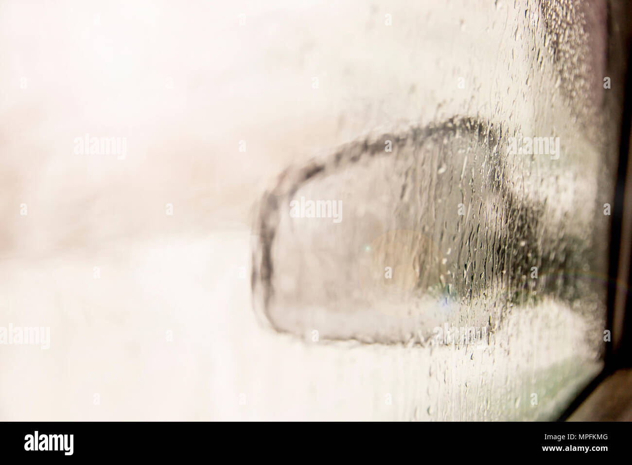 Seite Auto Rückspiegel durch Fenster mit Regentropfen verschwommen Stockfoto