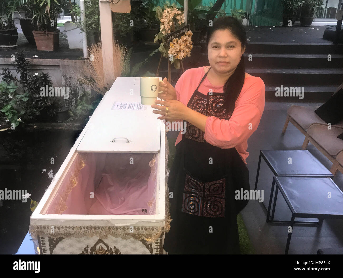 16. Mai 2018, Thailand, Bangkok: Mitarbeiter Rani Kwanmuang steht vor dem offenen Sarg bei der 'Death-Café "Kid Mai (lit. 'Neue' Denken). Ziel der Einrichtung ist, Besucher mehr Bewußtsein ihrer eigenen Sterblichkeit zu machen. Foto: Christoph Sator/dpa Stockfoto