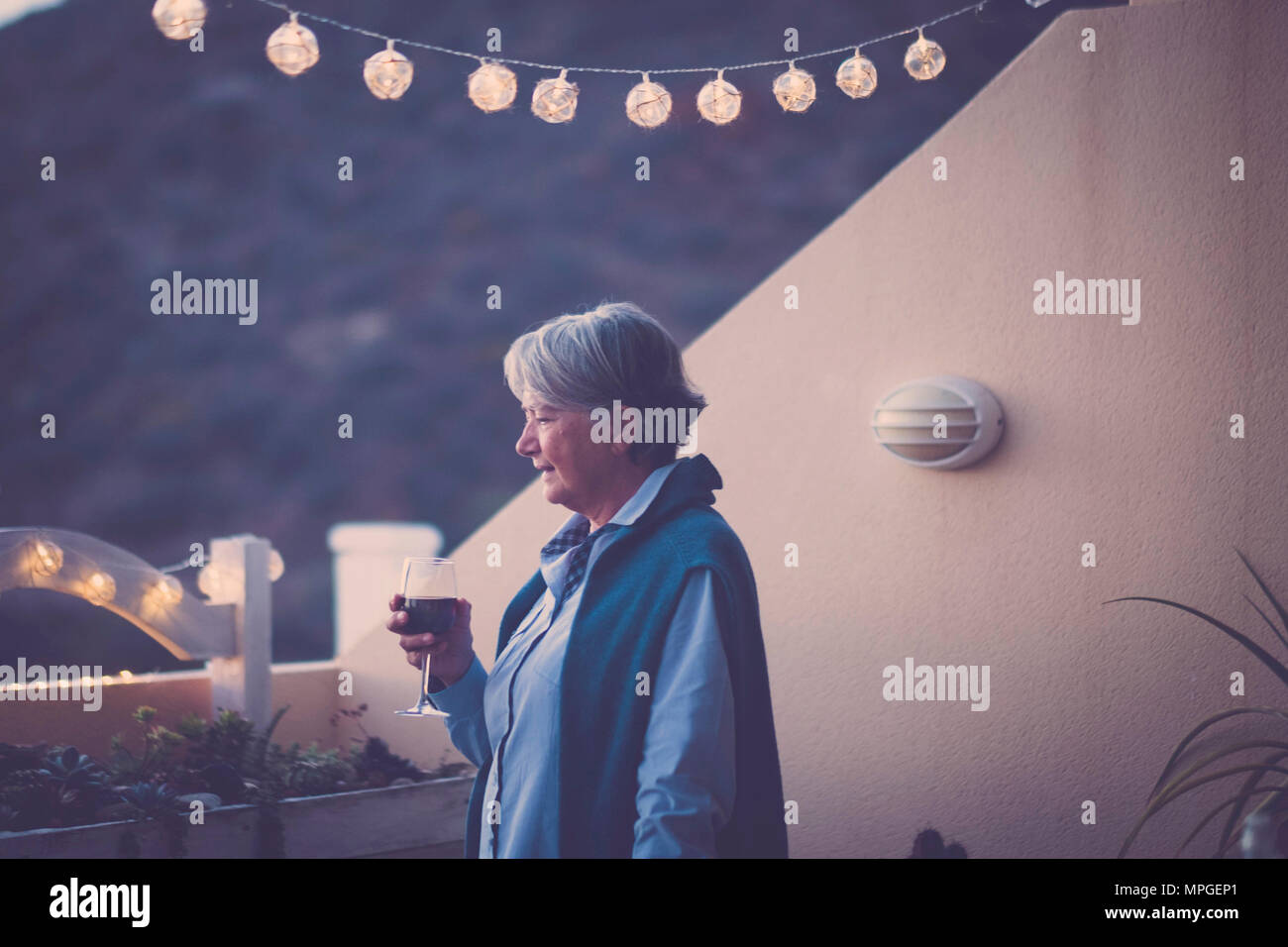 Im Alter ältere Frau trinkt Wein während einer festlichen Veranstaltung in der Nacht im Urlaub. Sommer style und die Berge Blick in die Natur. Schönen nach Modell lifes Stockfoto Im Alter ältere Frau trinkt Wein während einer festlichen Veranstaltung in der Nacht im Urlaub. Sommer style und die Berge Blick in die Natur. Schönen nach Modell lifes Stockfoto