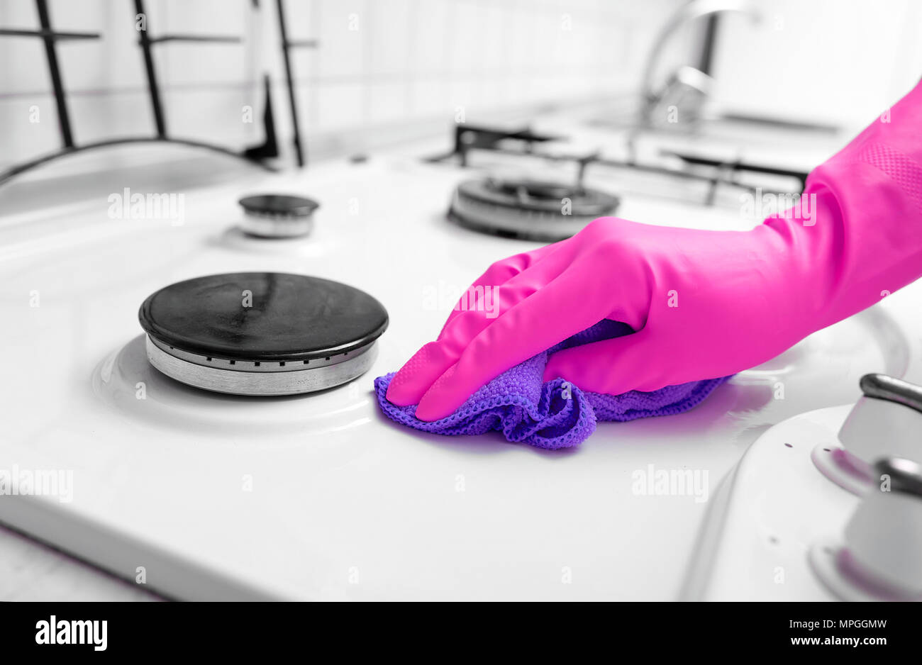 Hand in Gummihandschuhe reinigt eine Küche Gasherd. Stockfoto