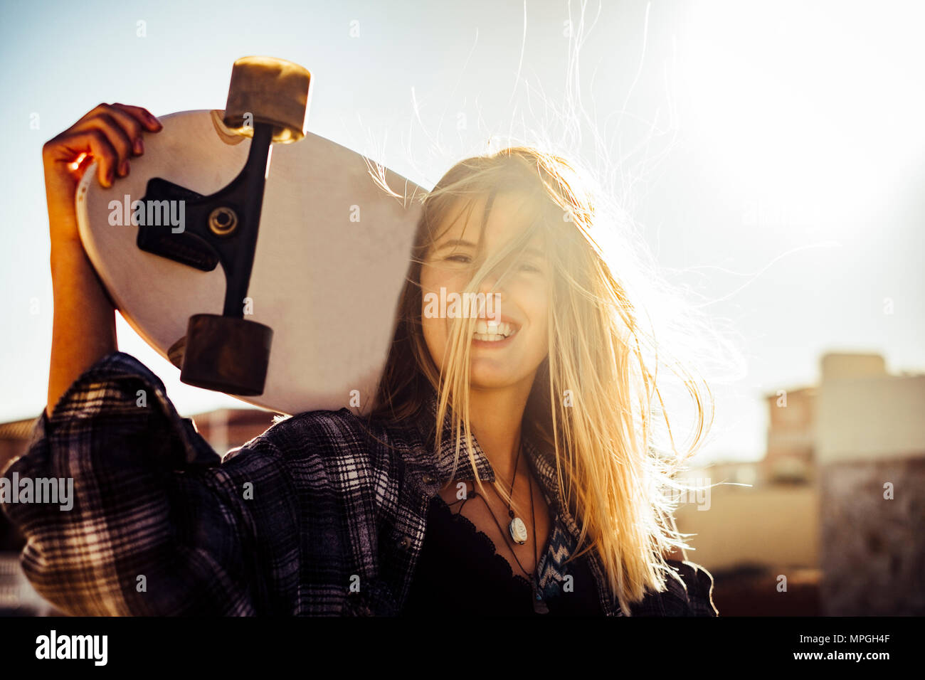 Schön caucasiamo blonde Modell freie Frau mit einem Skateboard in der Sonne Hintergrundbeleuchtung bei Sonnenuntergang. Freiheit und Unabhängigkeit Jugend Konzept auf Teneriffa. Hair Stockfoto