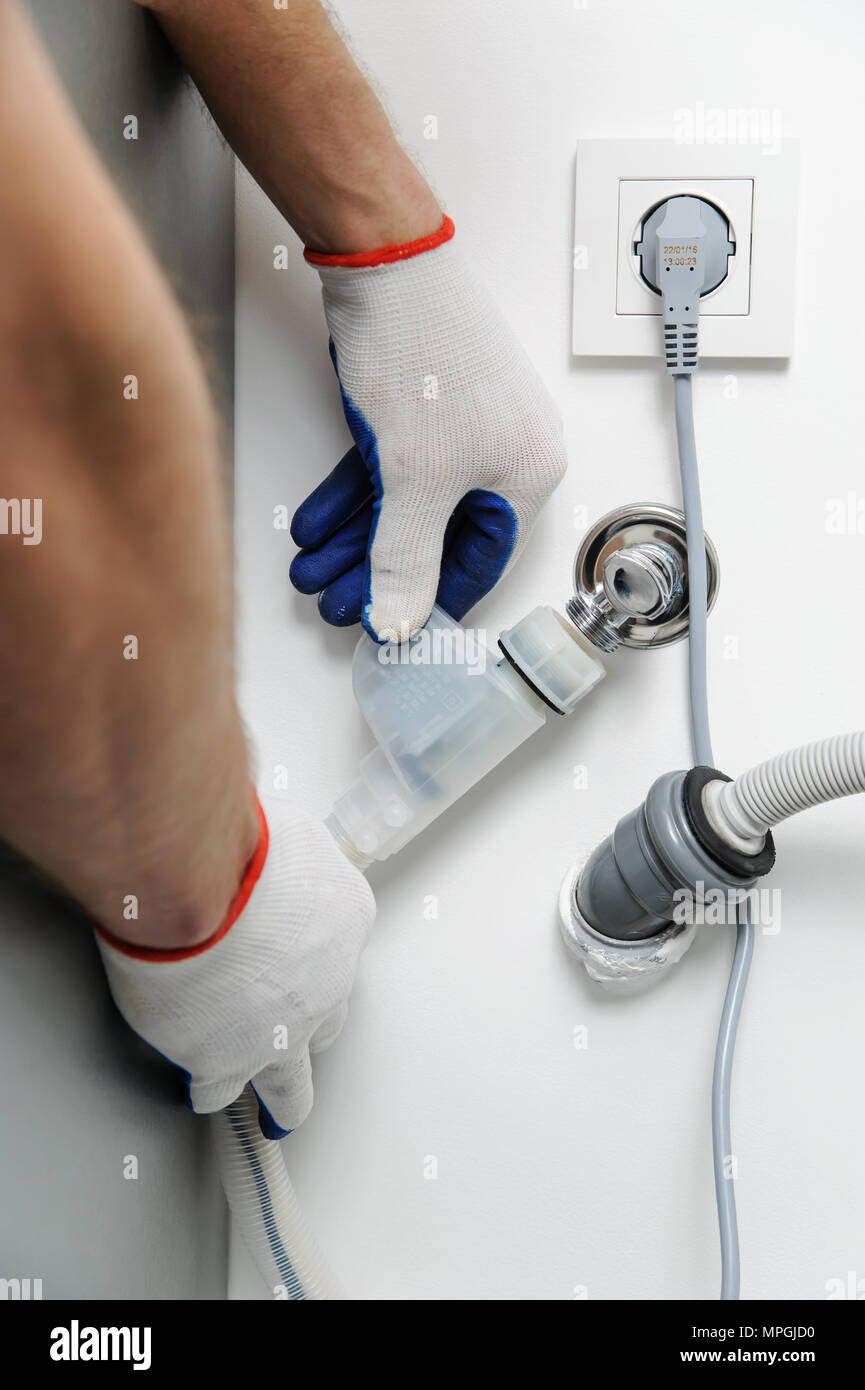 Installation von Haushaltsgeräten. Arbeiter beimisst, ein Wasserschlauch mit dem Ventil. Stockfoto