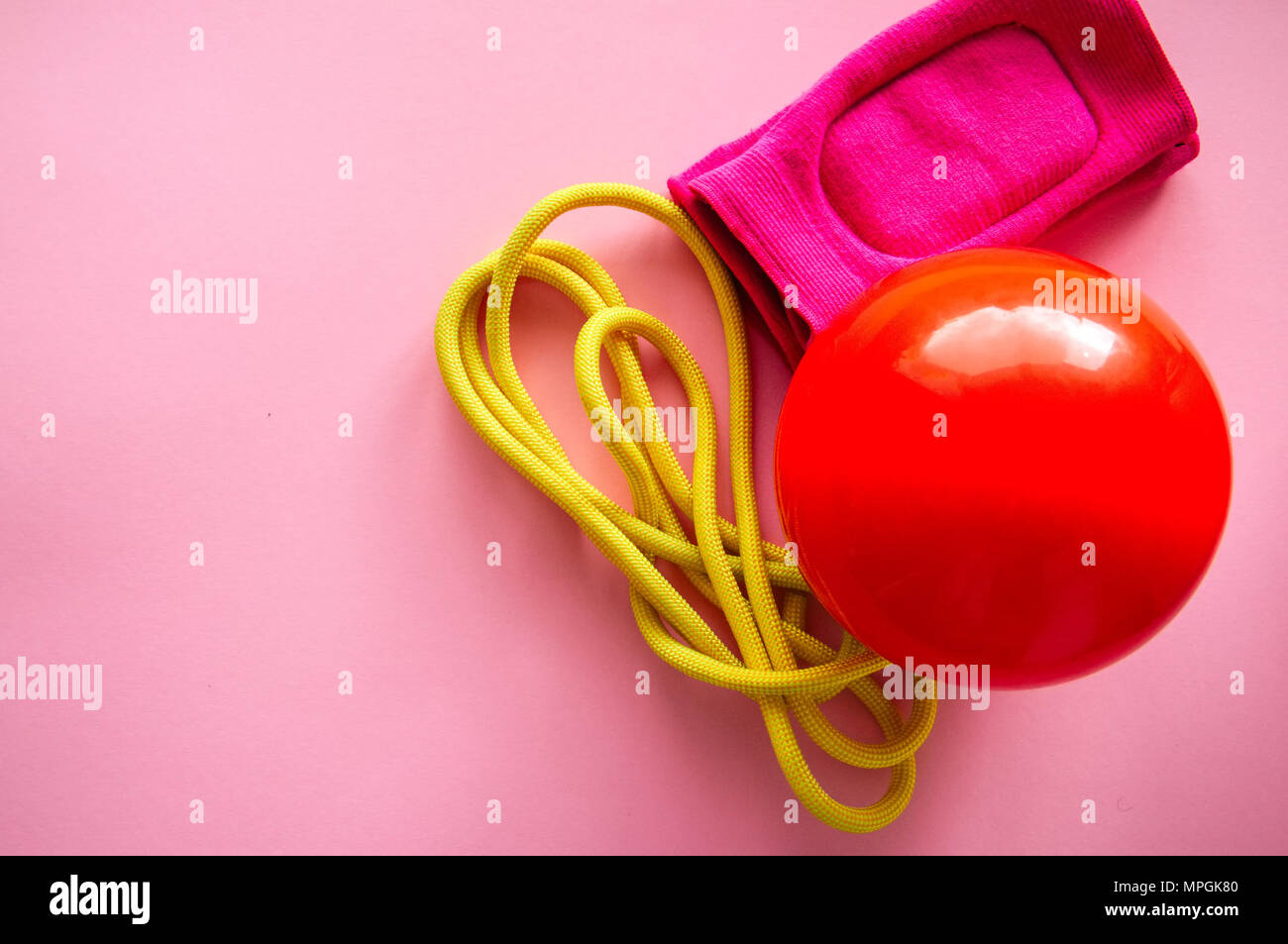 Rot Gymnastikball, Knieschoner und Springseil auf einem rosa Hintergrund. Sport, Hobby und Lifestyle Konzept. Top ansehen und kopieren. Stockfoto