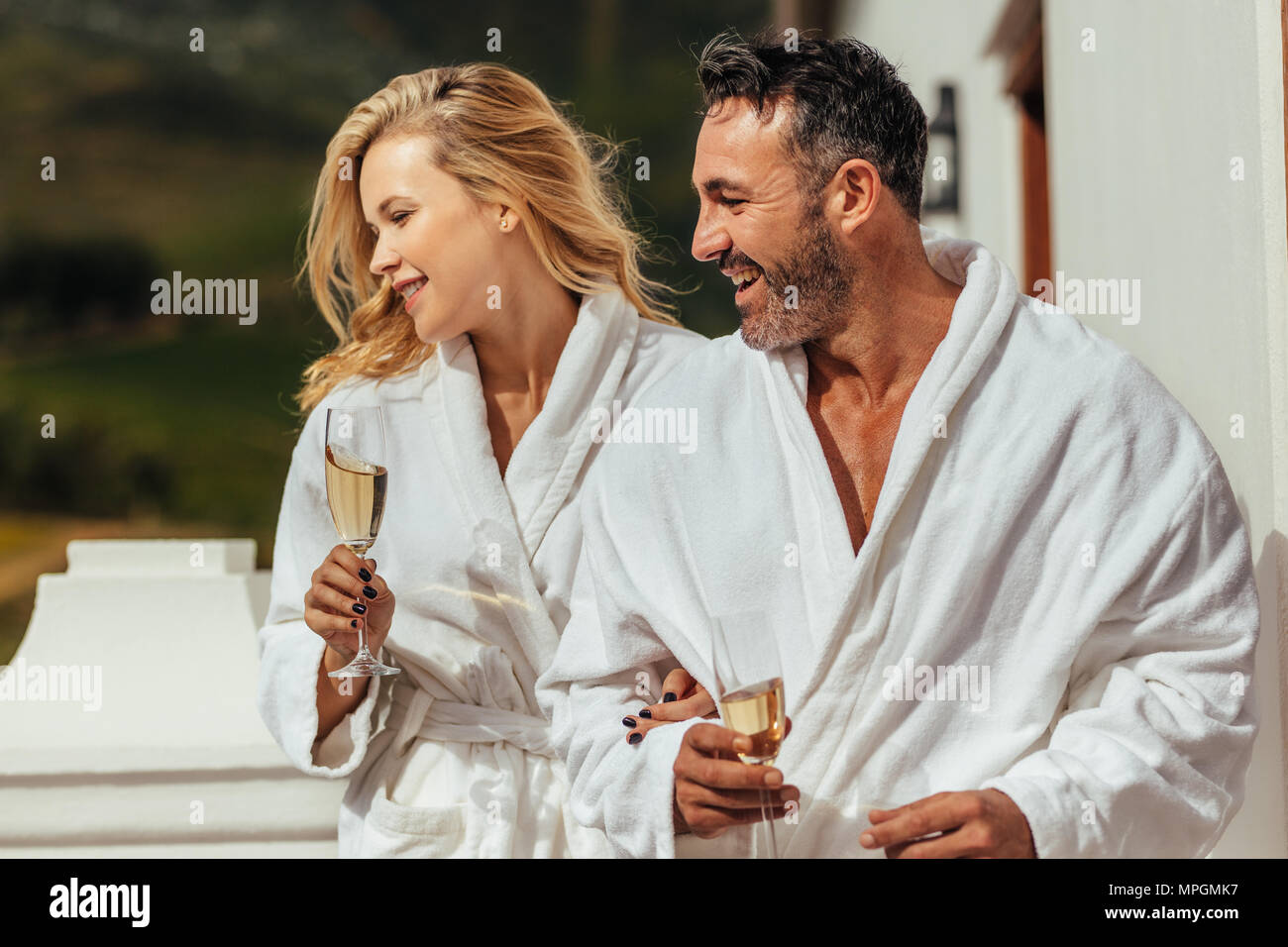 Mann und Frau im Bademantel mit Gläsern Wein weg schauen und lächeln. Paar  tragen Bademäntel in Luxus Villa Balkon stehen Stockfotografie - Alamy