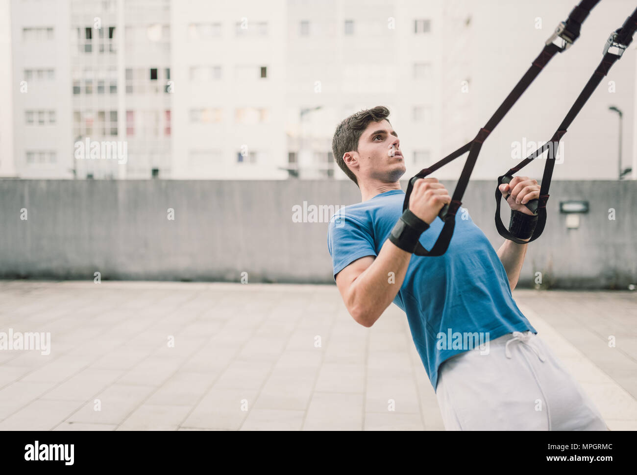 Der Mensch macht crossfit Push-ups mit trx fitness Bänder in der Straße Stockfoto