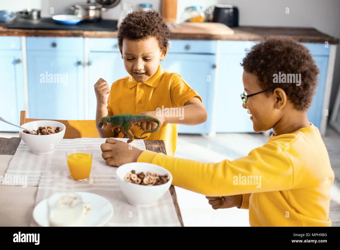 Nette kleine Kinder spielen mit Dinosaurier beim Frühstück Stockfoto