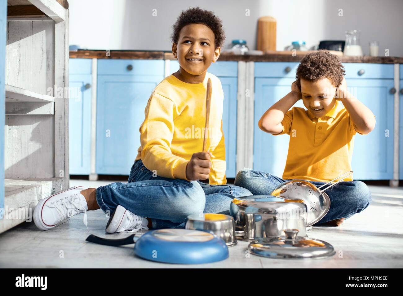 Upbeat kleine Jungen erzeugen laute Geräusche durch Trommeln auf kochtöpfen Stockfoto