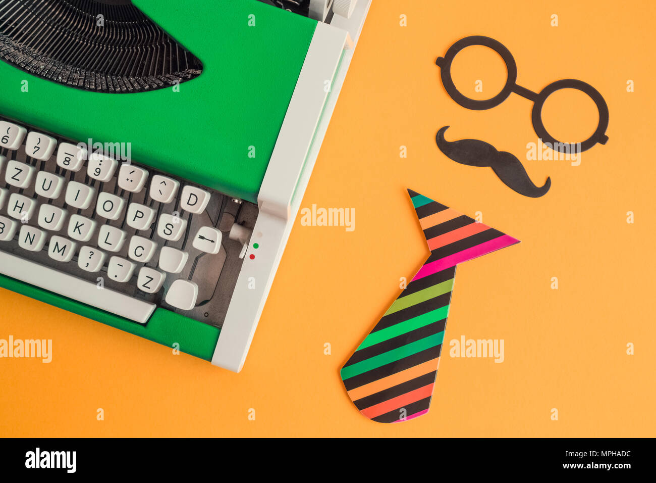 Flach vintage green Schreibmaschine und Papier stützen in Form von Retro hipster Mann auf orangefarbenem Hintergrund minimal kreatives Konzept. Stockfoto