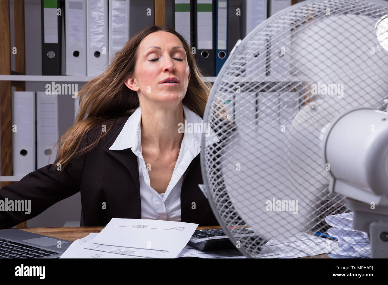 Reife Geschäftsfrau Kühlung sich Vor Ventilator bei heißem Wetter Stockfoto