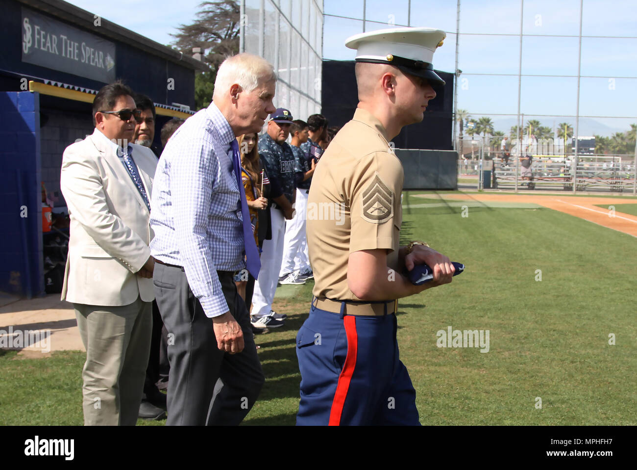 Marine Corps Recruiters SSgt. Phillip Seite der einziehenden Unterstation Lakewood und Dennis Mulhaupt, Präsident der St. Johannes Bosco High School, zu Fuß auf der Fahnenstange die amerikanische Flagge während einer Zeremonie vor dem Spiel Baseball in St. Johannes Bosco, Glockenblume, Calif., 14. März 2017 zu erhöhen. Stockfoto