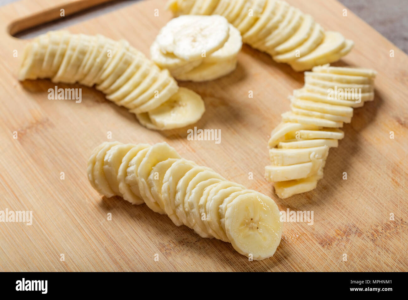 Frische rohe Bananenscheiben auf Holz Schneidebrett - Nahaufnahme Stockfoto