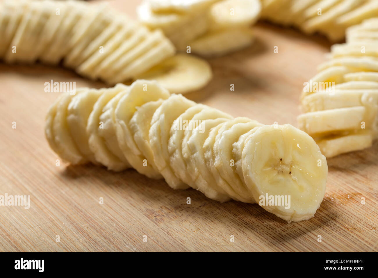 Frische rohe Bananenscheiben auf Holz Schneidebrett - Nahaufnahme, selektiver Fokus Stockfoto