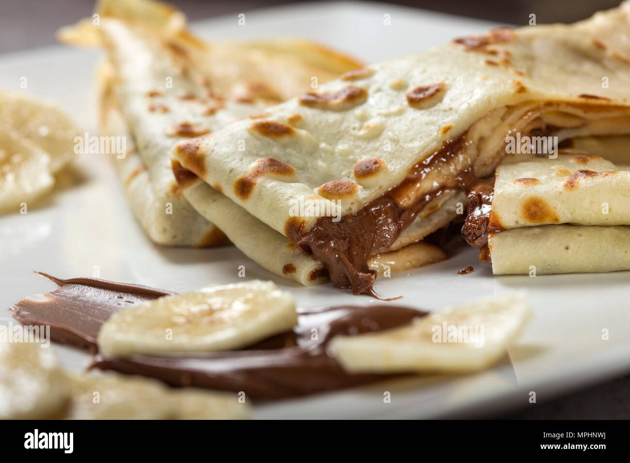 Im französischen Stil Pfannkuchen mit Banane, Schokolade Soße auf eine weiße Platte, Ansicht schließen Stockfoto
