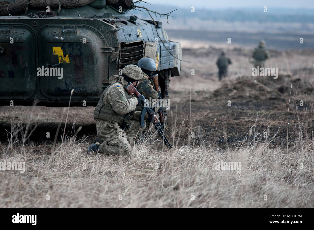 Ukrainische Soldaten der 1.Bataillon, 28 Mechanisierte Infanteriebrigade Abdeckung hinter dem BMP-2 gepanzertes Fahrzeug, während andere Soldaten vor Rush einen Draht Hindernis voraus Ihrer Einheit blockieren während der Ausbildung an der Yavoriv Combat Training Center des internationalen Friedens und der Sicherheit, in der Nähe der Yavoriv, Ukraine am 16. März zu verletzen. Die 1-28 mechanisierte Infanterie Brigade ist eine Ausbildung bei der CTC, wo die Gemeinsame Multinationale Ausbildung Group-Ukraine, eine Koalition aus sieben Nationen, die Entwicklung der Combat Training Center und Professionalität in der ukrainischen Armee ist. (Foto durch Stockfoto