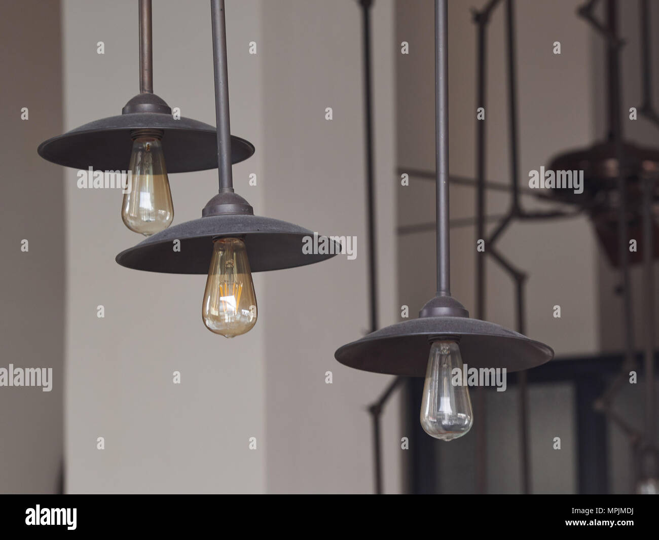 Metall schwarz Deckenleuchte mit gelben elektrischen Leuchten auf eine weiße Wand im Hintergrund. Stockfoto