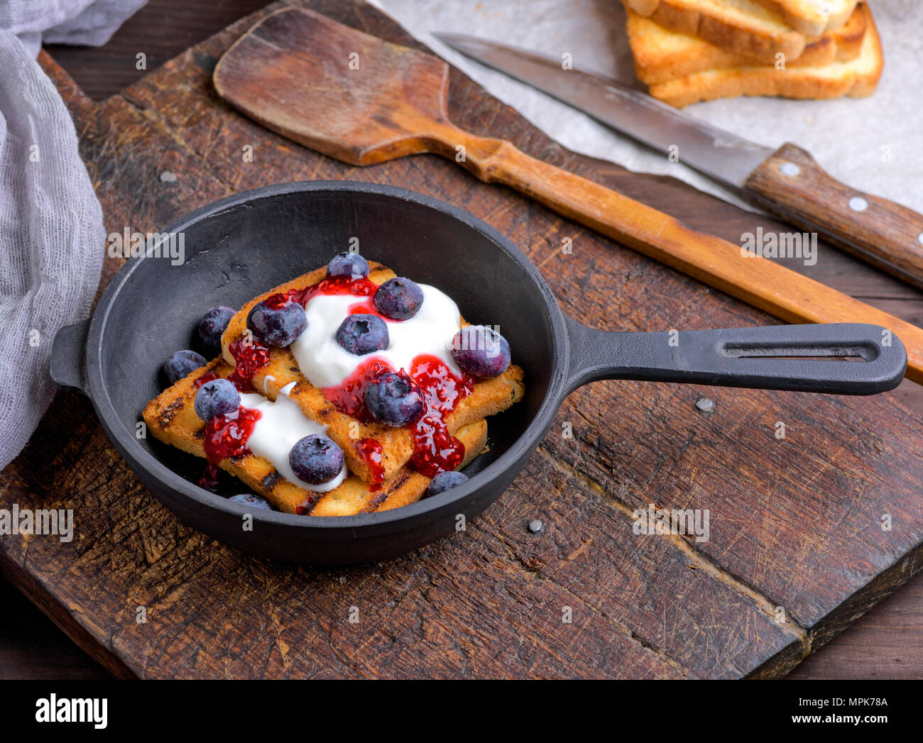 French Toast mit Beeren, Sirup und saure Sahne in einem schwarzen gusseisernen Pfanne, Ansicht von oben Stockfoto