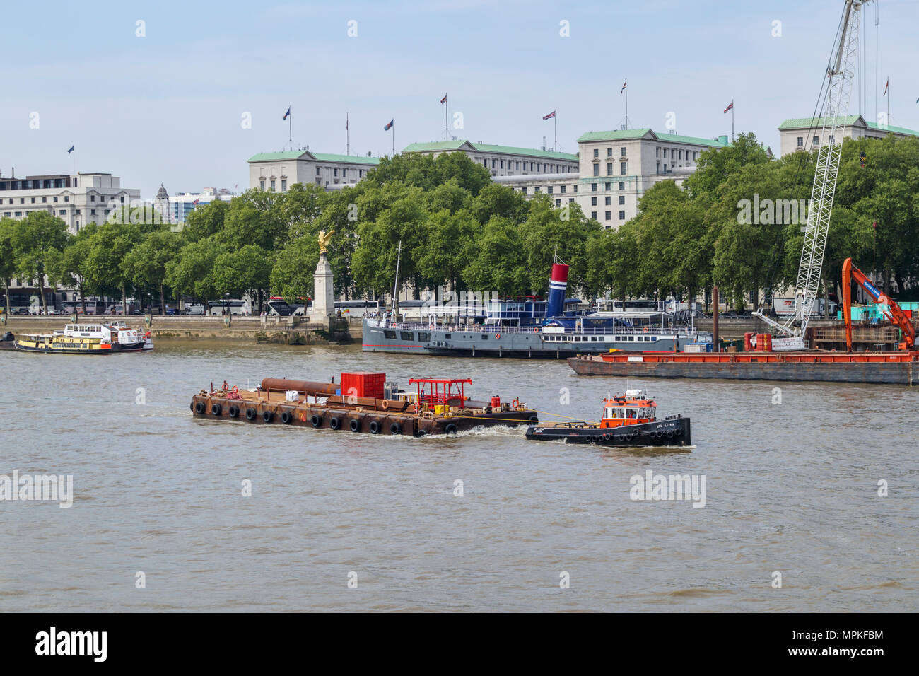 Tugboat GPS Illyria zieht ein lastkahn Bereitstellung von Baumaterialien durch Victoria Embankment Vorland auf der Themse, London Stockfoto