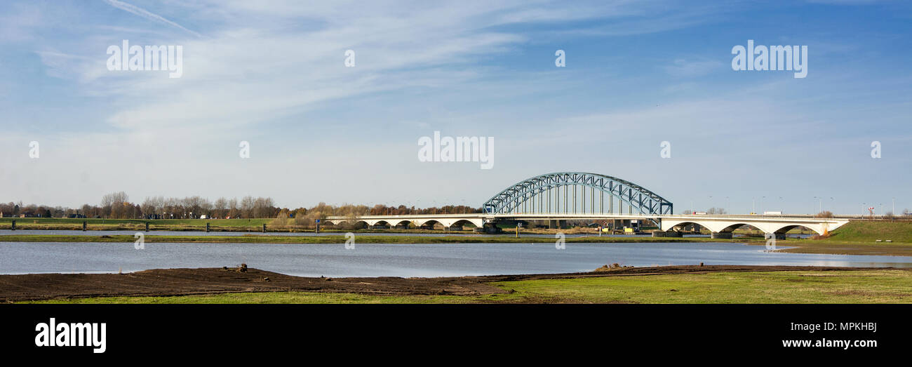 Typisch Holländischen IJssel Landschaft mit blauer Himmel, weiße Wolken, Brücke, Wind und sonniges Wetter Stockfoto