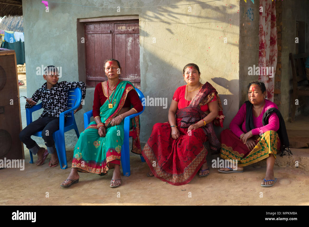 Nepalesische Frauen aus der Tharu ethnische Gruppe sitzt vor einem Haus während einer Hochzeit, Chitwan, Nepal Stockfoto