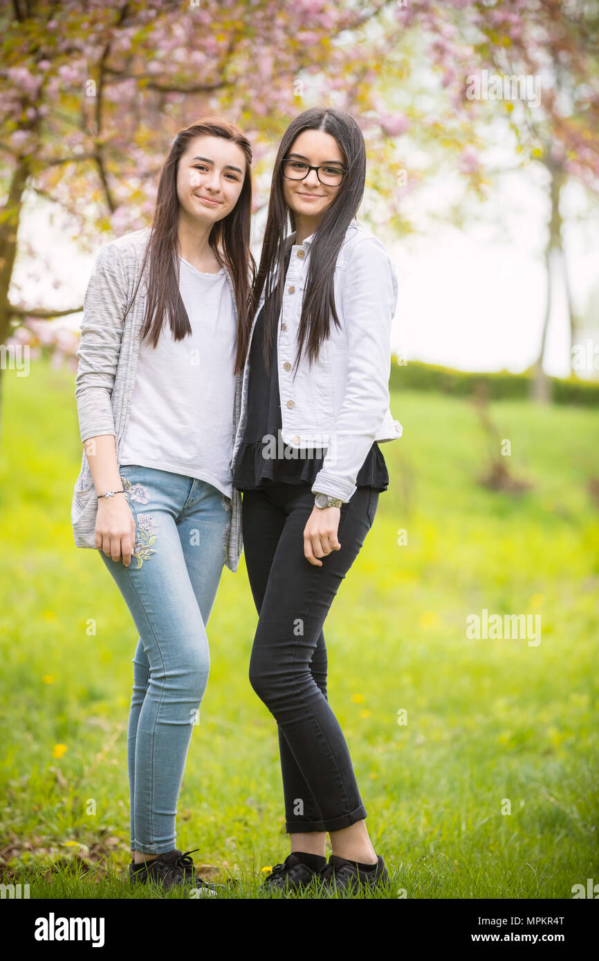 Zwei hübsche Schwestern Mädchen sich gemeinsam amüsiert, das Tragen modischer Kleidung, positive Emotionen. Mädchen auf der Suche an Kamera Stockfoto