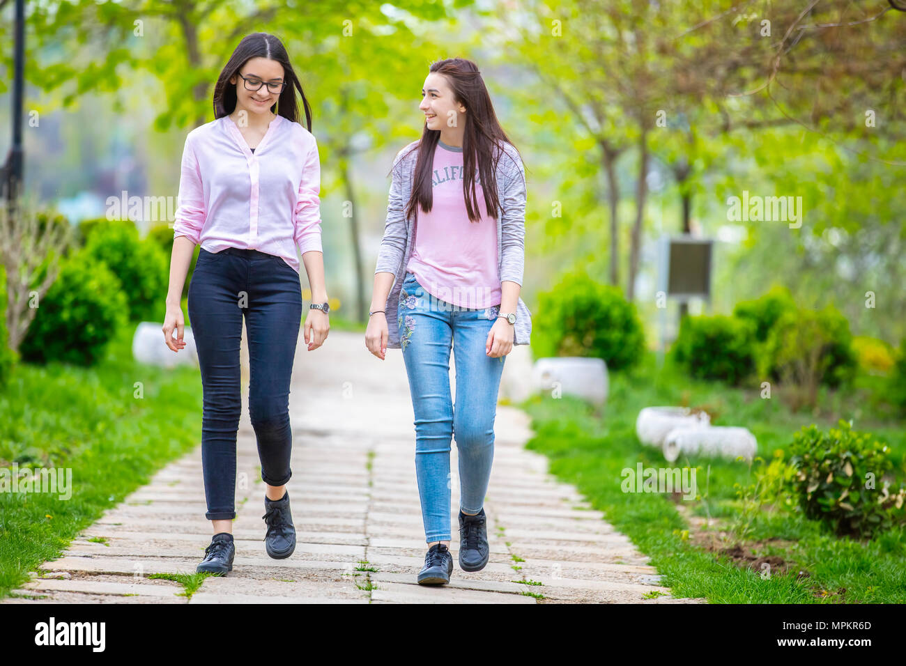 Zwei hübsche Schwestern Mädchen zu Fuß und Spaß zusammen haben im Park im Frühling. Stockfoto
