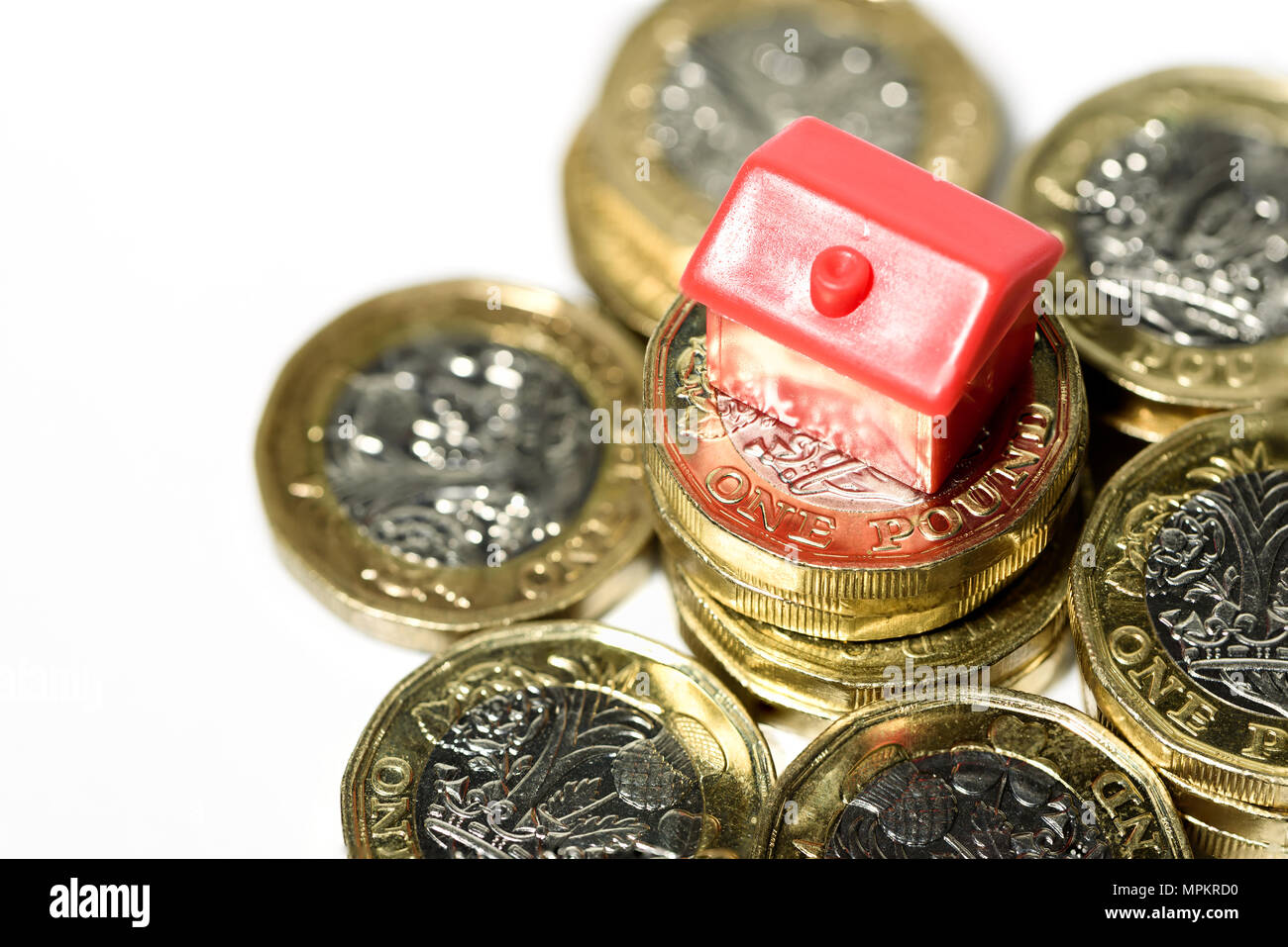 Makro Nahaufnahme eines kleinen Hauses ruht auf neue Pfund Münzen mit einem weißen Hintergrund. Stockfoto