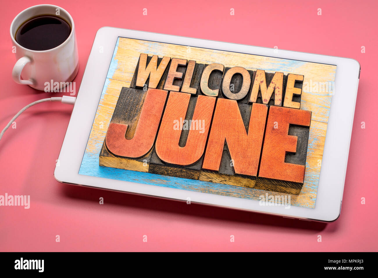 Willkommen Juni Banner - Wort in Vintage buchdruck Holz Art Abstract auf einer digitalen Tablette mit einer Tasse Kaffee Stockfoto