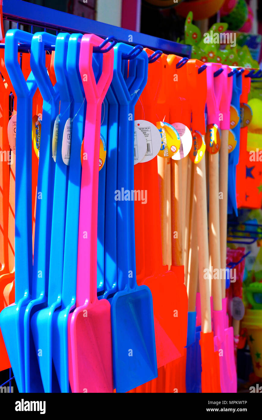 Kunststoff Strand Spaten bunte Kinder hängen von Rack für den Verkauf außerhalb Seaside shop, Blackpool, Lancashire, Großbritannien Stockfoto