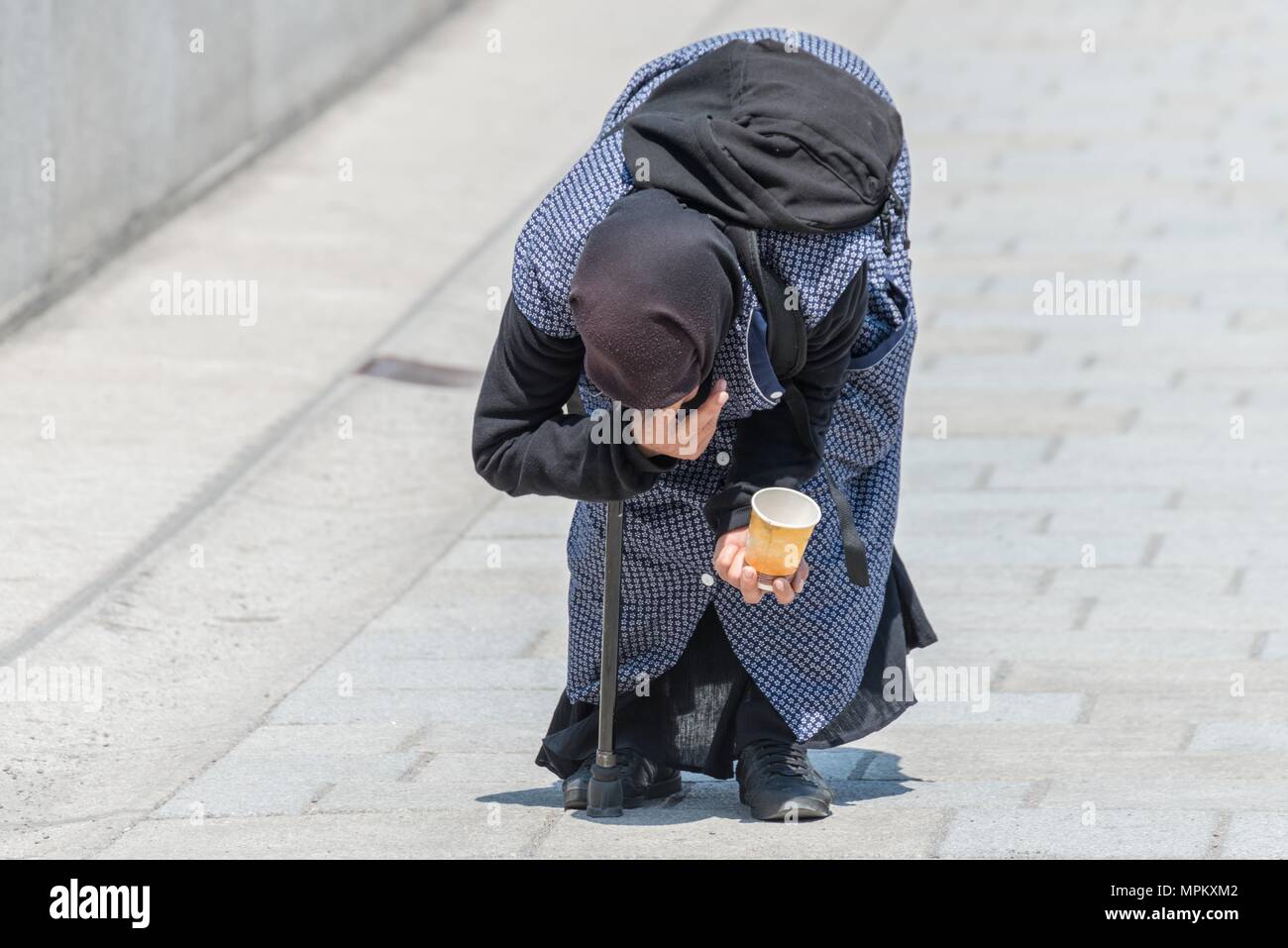 Alte Bettler Frau beugte sich über in einer Fußgängerzone, Deutschland Stockfoto