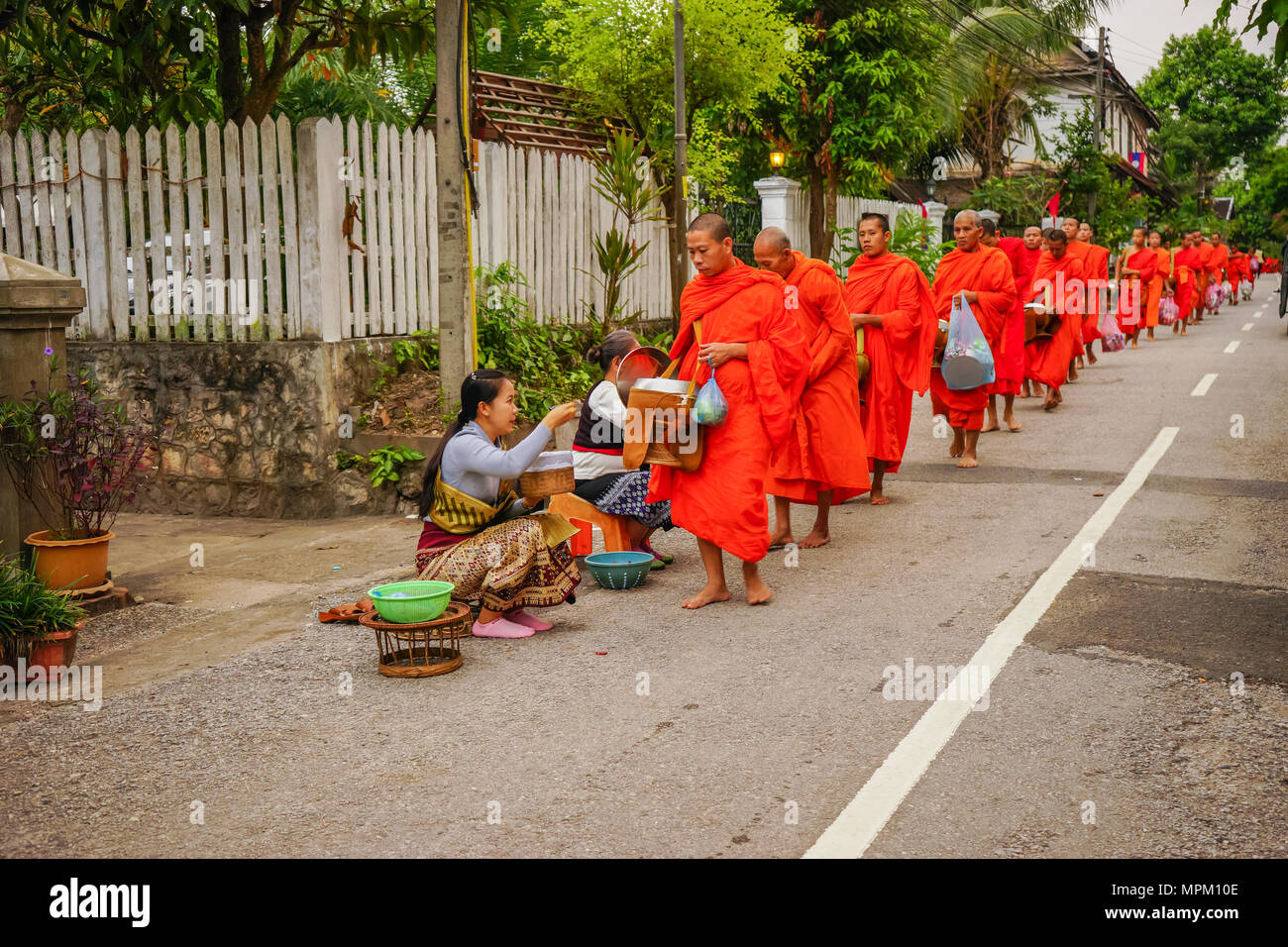 Luangprabang, Laos - Dezember 8, 2015: Laos Menschen mit Speisen und Dinge zu Gruppe von buddhistischen Mönchen in Morgen auf die ländliche Straße in Luangprabang, Lao Stockfoto