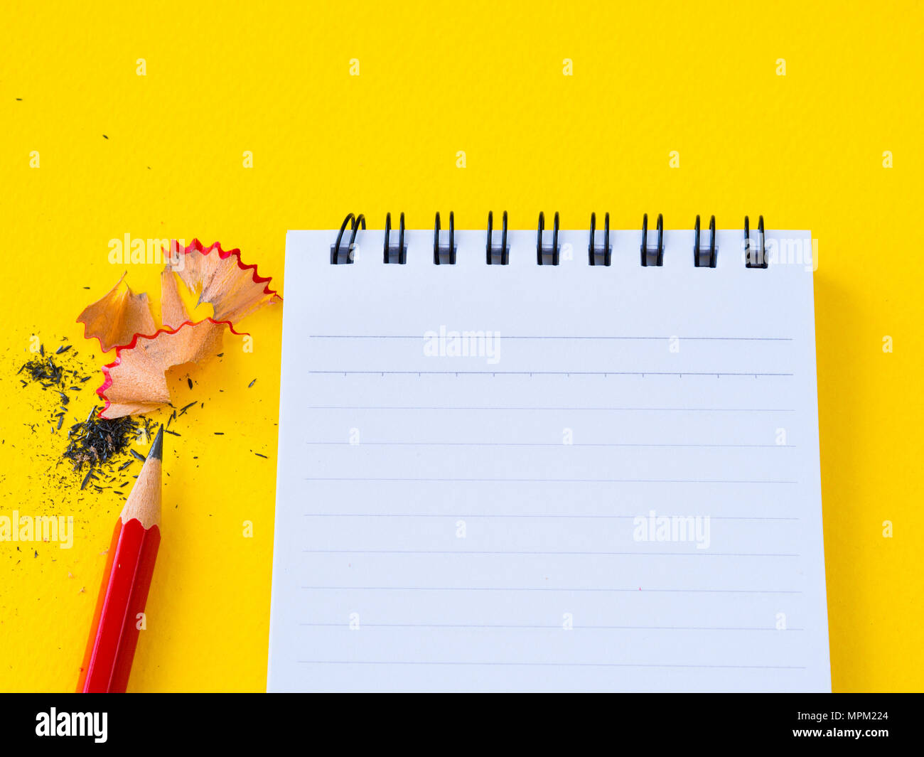 Schärfen eines roten Bleistiftspitzer und die Notiz Buch auf gelben Hintergrund. Stockfoto