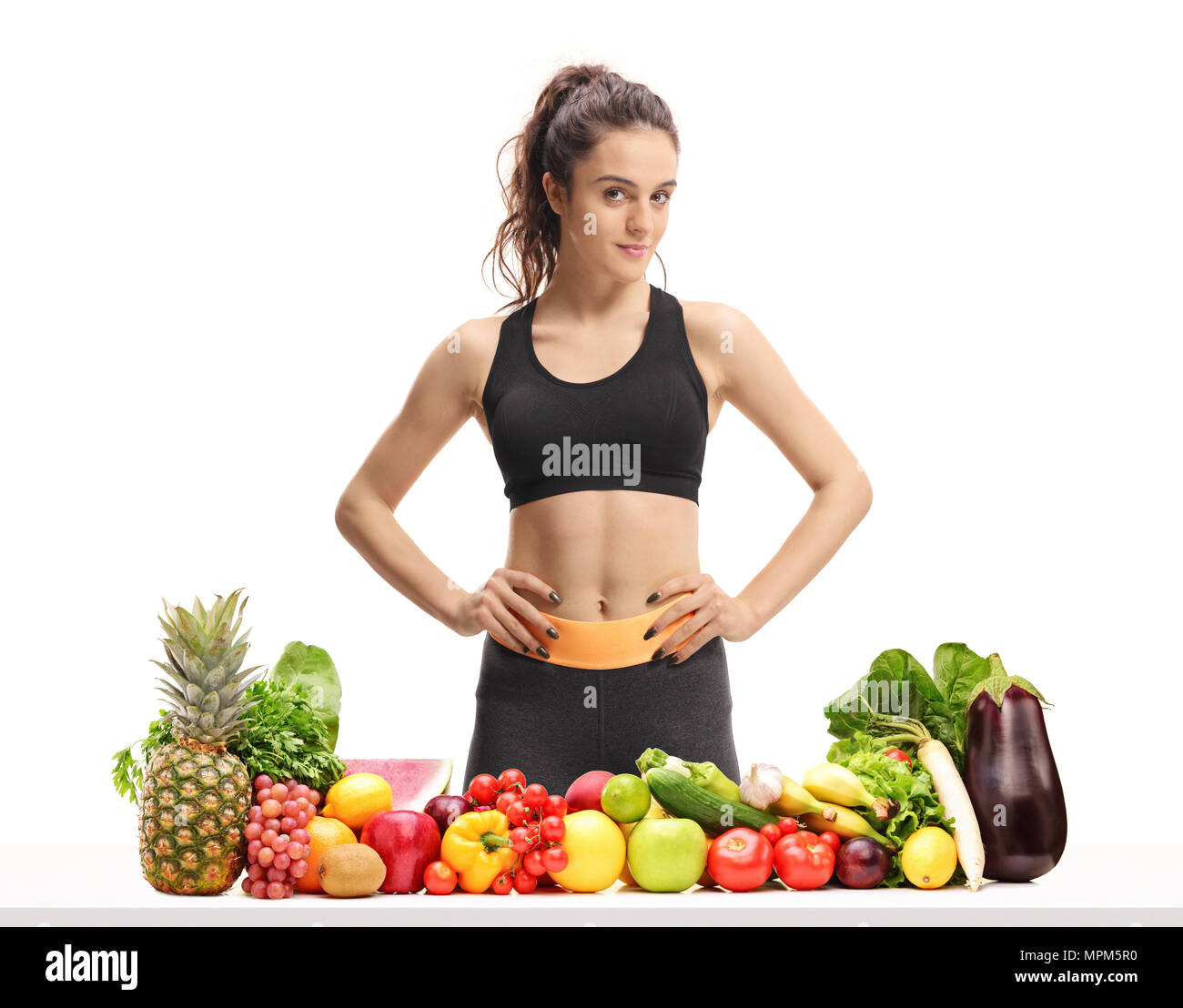 Fitness Frau hinter einem Tisch mit Obst und Gemüse auf weißem Hintergrund Stockfoto