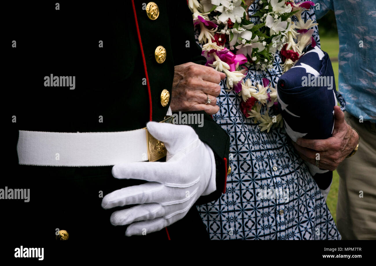 Taff Sgt. Kendrix D. Graham escorts Nancy Hazelbaker nach der Trauerfeier für ihren Ehemann, pensionierter Marine Col. Vincil W. Hazelbaker, an der Hawaiianischen Memorial Park Friedhof am 24. März 2017. Nach der Zeremonie, Hubschrauber aus marinen Flugzeuge Gruppe 24 führte eine fehlende Mann Formation, die eine Antenne salute während ein Flypast von Flugzeugen an einer Gedenkfeier durchgeführt, in der Regel in Erinnerung an einen gefallenen Piloten. Hazelbaker war ein Marine Piloten, im Militär für 34 Jahre gedient. Während seines Dienstes, flog er mehr als 680 Einsätze und erwarb die Marine Kreuz für seine außerordentlichen Er Stockfoto