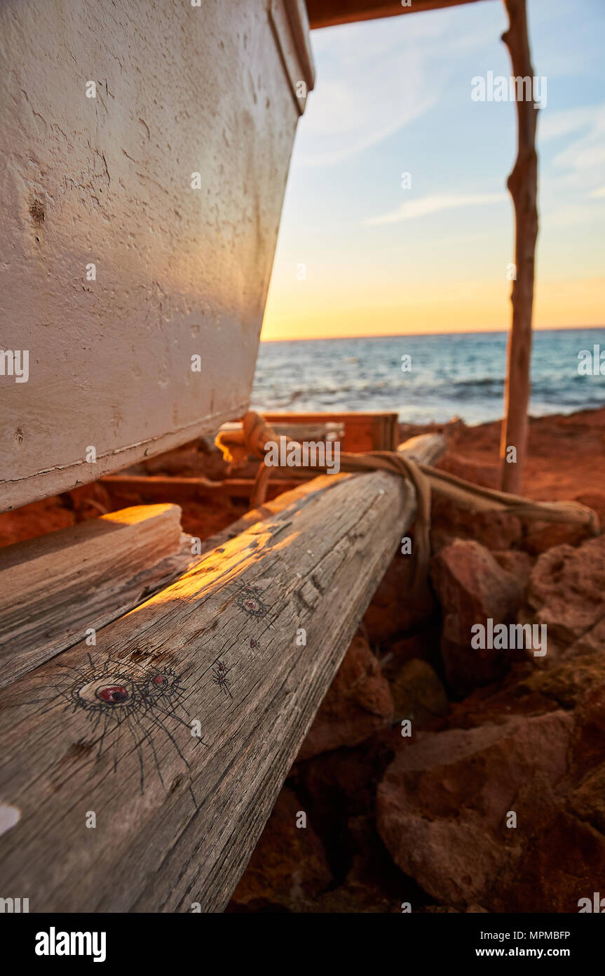Boot am traditionellen Holzboothaus Stand mit Zeichnungen am Meer bei Sonnenuntergang am Caló d’en Trull bei Cala Saona in Formentera (Balearen, Spanien) Stockfoto