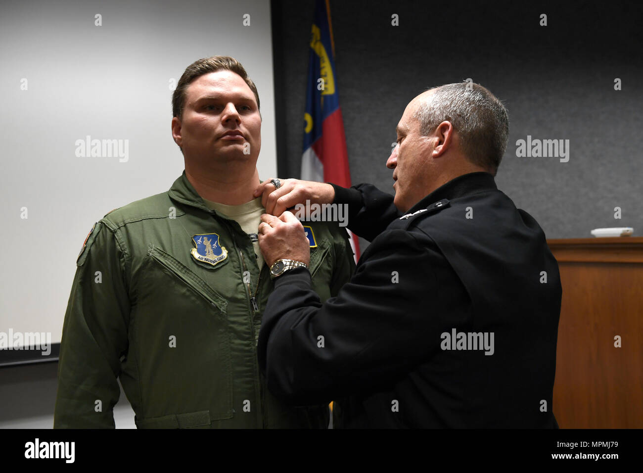 Us-Armee Generalmajor Greg Lusk (Mitte), der Adjutant General von Nord-carolina, Kommandant der North Carolina National Guard, Stifte der North Carolina National Guard Soldat und Flieger-Medaille für Heldentum auf US Air Force Maj. Nathan Barron (links), 156 Airlift Wing, während einer Zeremonie an der North Carolina Air National Guard Base, Charlotte Douglas International Airport, 1. April 2017 statt. Barron handelte entschlossen und mutig durch die Bekämpfung und Manövrieren einen widerspenstigen Passagier auf den Boden, nachdem er ein Flugbegleiter angegriffen. Barron Fortsetzung der Passagier zu unterwerfen, bis Gesetz enforcemen Stockfoto