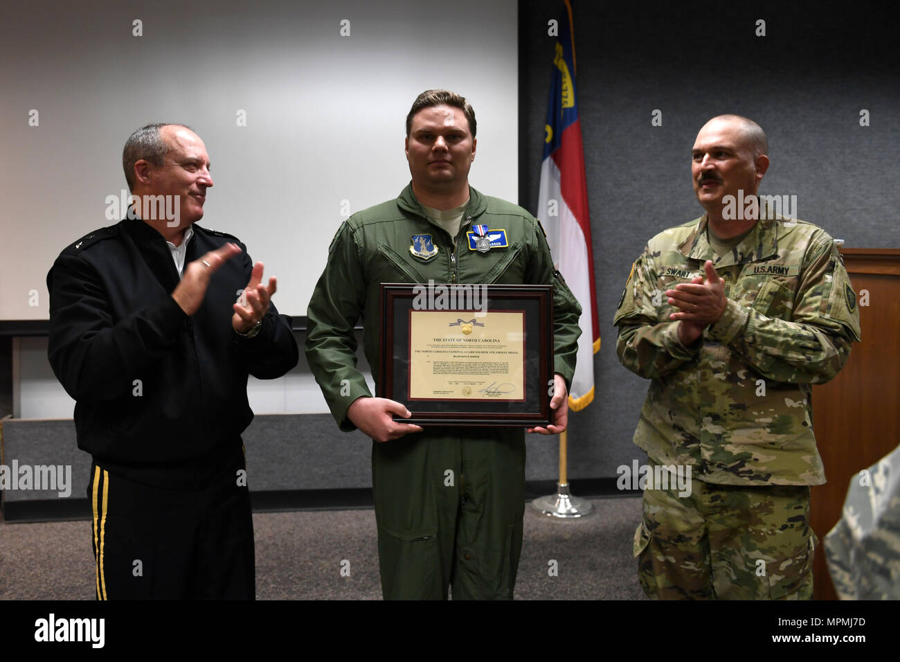 Us-Armee Generalmajor Greg Lusk (links), der Adjutant General von Nord-carolina, Kommandant der North Carolina Nationalgarde und U.S. Army Command Sgt. Maj. Johannes Swart (rechts), den Befehl Sergeant Major der North Carolina National Guard, geben eine Runde Applaus für US Air Force Maj. Nathan Barron (Mitte), 156 Airlift Squadron, nach ihm mit dem North Carolina National Guard Soldat und Flieger-Medaille für Heldentum im Rahmen einer Zeremonie in der North Carolina Air National Guard Base, Charlotte Douglas International Airport, 1. April 2017 statt. Barron, entschlossen und mutig gehandelt Stockfoto