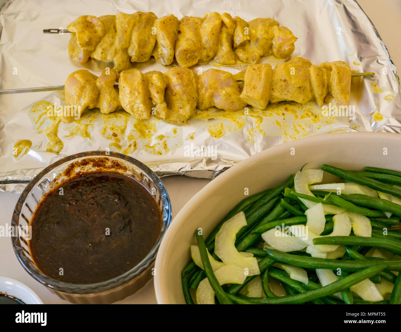 Indonesische Essen, für das Abendessen vorbereitet. Schiefe Hühnersaté auf vereitelt Fach, Erdnuß-Sauce, kecap masin Sauce und grüne Bohnen mit Gurkensalat Stockfoto