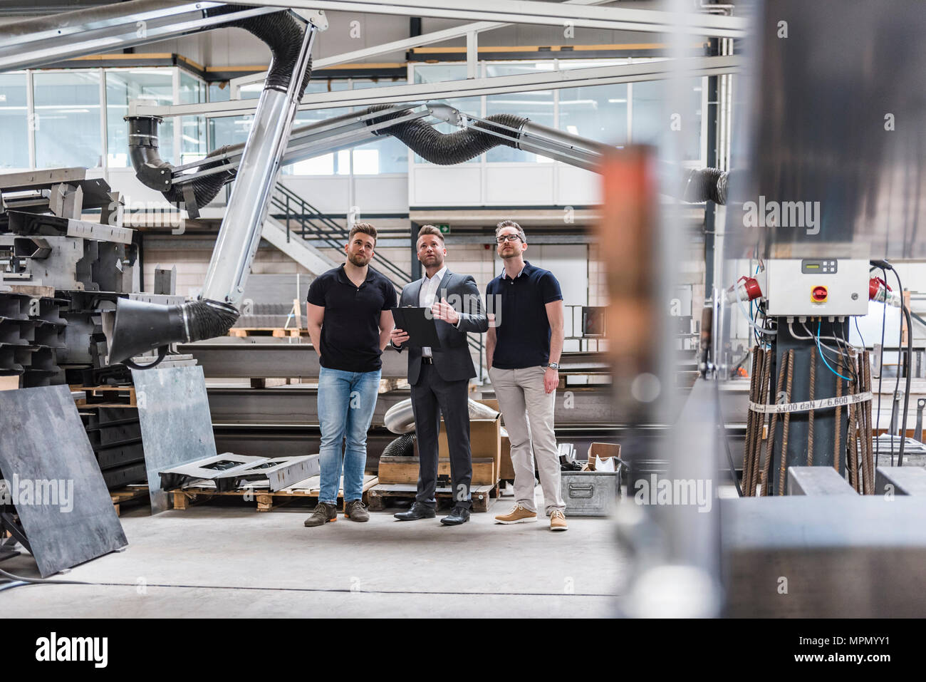 Drei Männer stehen und sprechen über Factory Shop Boden Stockfoto