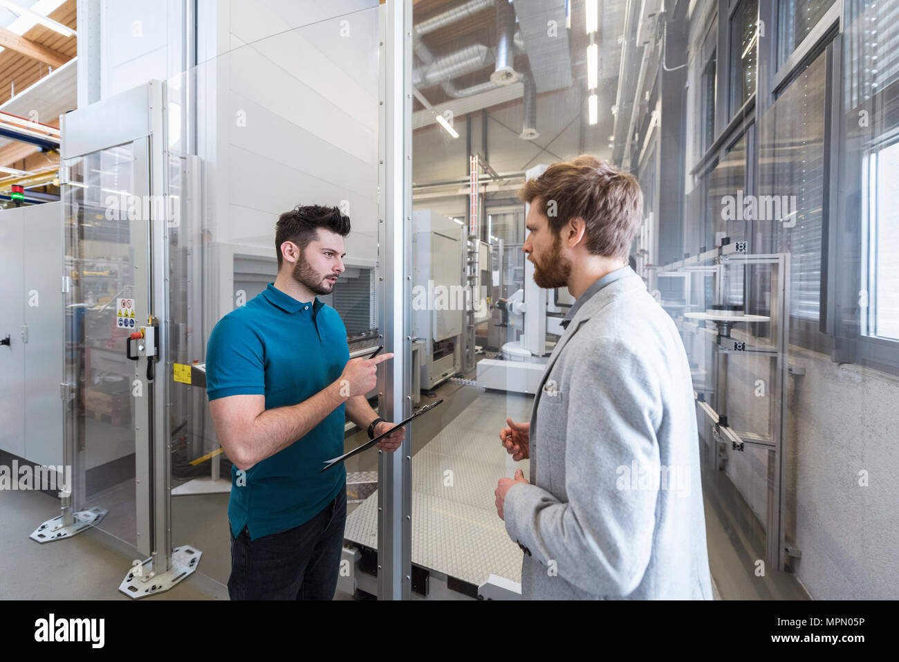 Unternehmer und Mitarbeiter diskutieren in der modernen Fabrik Stockfoto