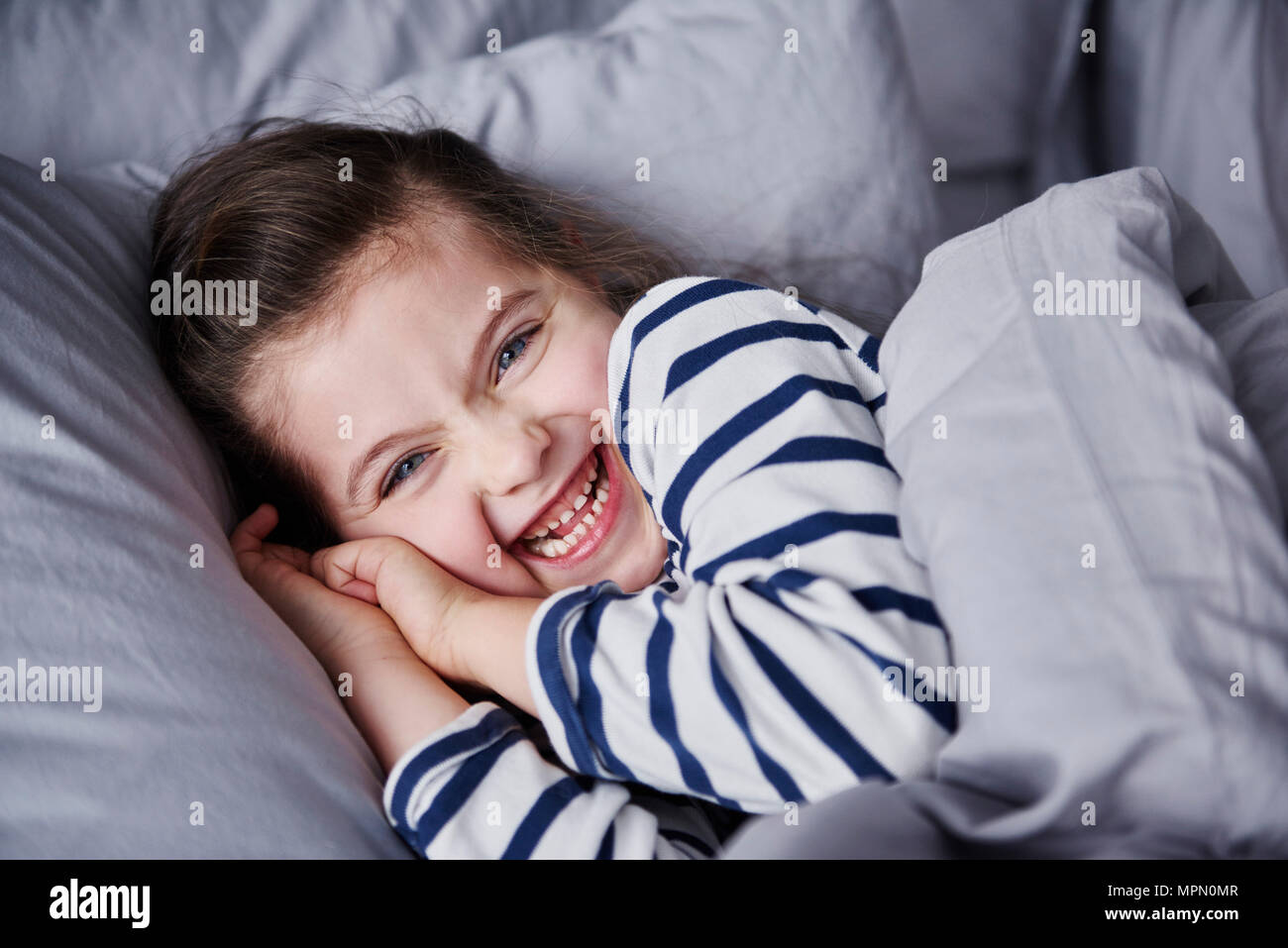 Portrait von Lachen kleines Mädchen im Bett lag, Stockfoto