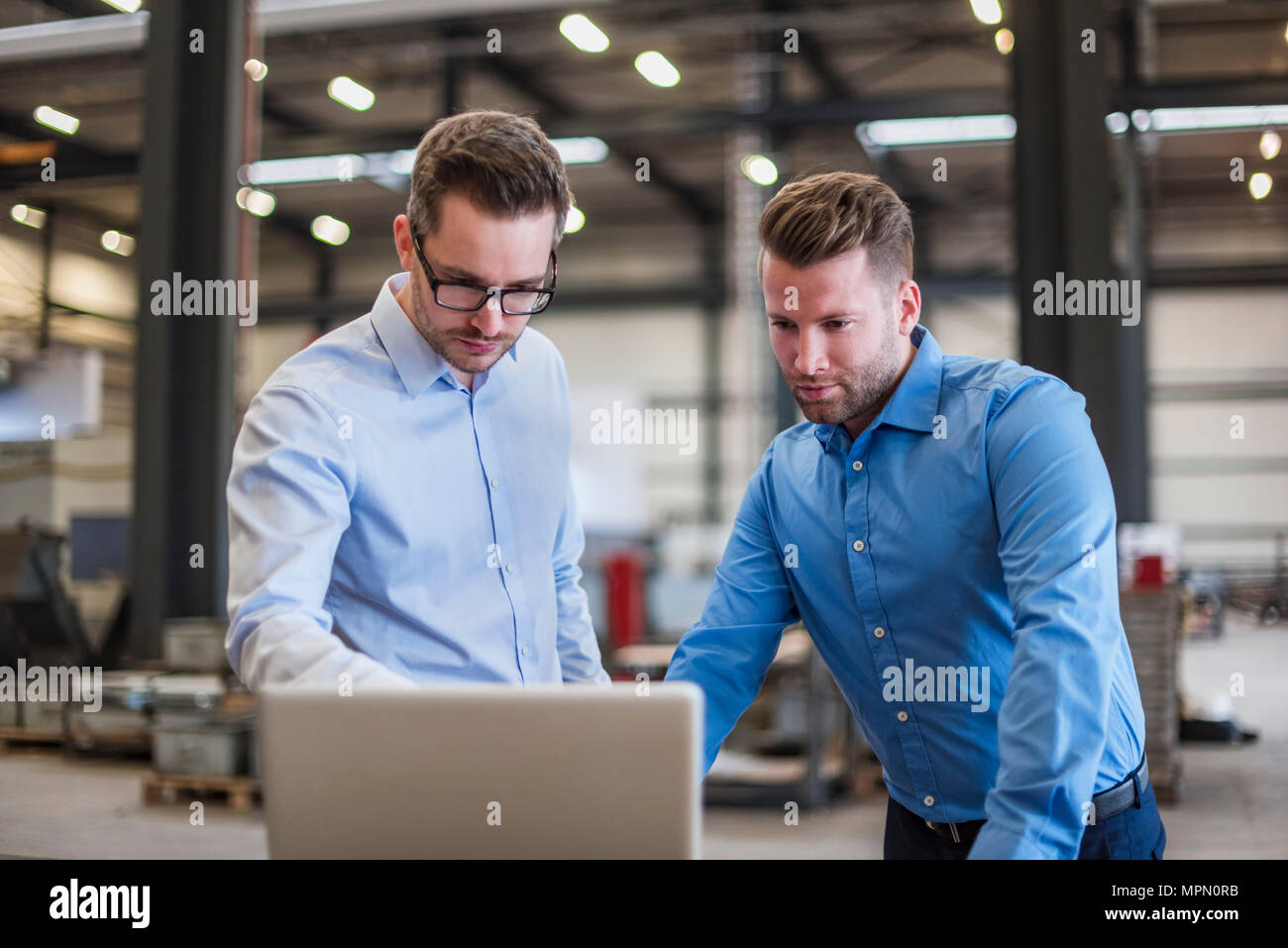 Zwei Geschäftsleute teilen Laptop auf Factory Shop Boden Stockfoto