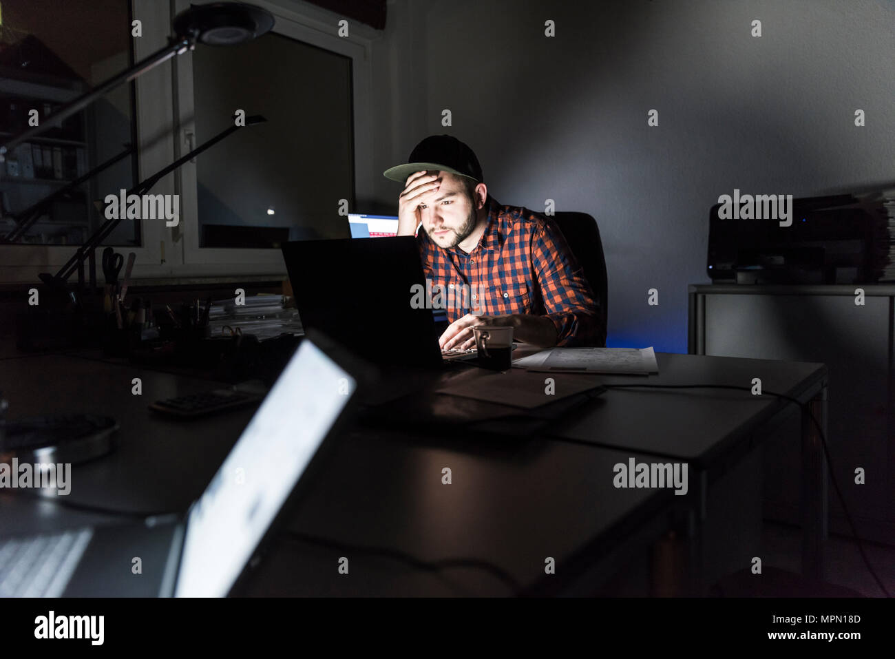 Portrait von freelancer Sitzen am Schreibtisch arbeiten am Laptop in der Nacht Stockfoto