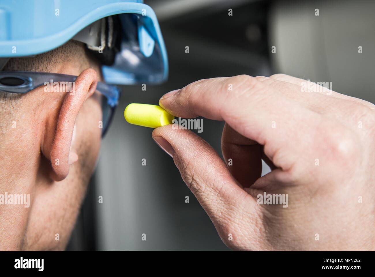 Ear Plugs Gehörschutz einfache Lösungen. Arbeiter in Blau harten Hut Vorbereitung zu verwenden Schaumig. Stockfoto